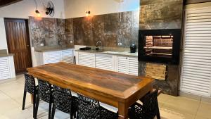 a kitchen with a wooden table and a fireplace at Casa Pé na Areia com Piscina Climatizada in Bertioga