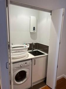 una pequeña cocina con lavadora y fregadero en Large Executive 3 bedroom, en Yarralumla