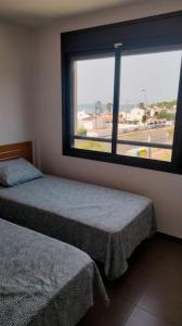 1 Schlafzimmer mit 2 Betten und einem großen Fenster in der Unterkunft Frente mar, piscina, Delta in Alcanar