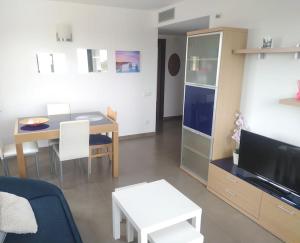 ein Wohnzimmer mit einem Sofa, einem Tisch und einem TV in der Unterkunft Frente mar, piscina, Delta in Alcanar