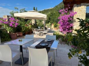un patio con mesas, sillas y flores púrpuras en La Cascata Negli Ulivi, en Toscolano Maderno