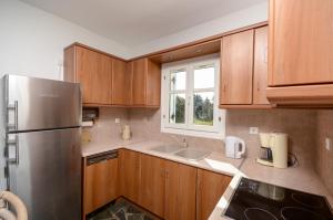 a kitchen with wooden cabinets and a stainless steel refrigerator at White Cedar Villa in Stelida