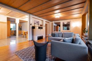 a living room with two blue couches and a kitchen at Hubertus Gartenlodge in Mittelberg