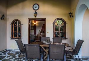 uma sala de jantar com mesa e cadeiras e um relógio em Platamon village house em Platamon