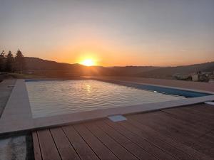 a swimming pool with a sunset in the background at Martins House in Arouca