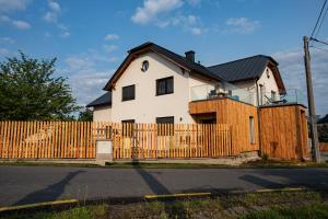 una casa blanca detrás de una valla de madera en Wellness Apartmány Vila Republika, en Velké Losiny