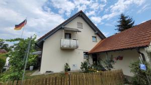 une maison blanche avec un drapeau devant elle dans l'établissement Ferienwohnung nähe Bodensee., à Meckenbeuren
