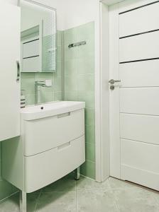 W białej łazience znajduje się umywalka i lustro. w obiekcie Apartament Kapitan w Świnoujściu
