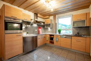 a large kitchen with wooden cabinets and a window at Hubertus Gartenlodge in Mittelberg