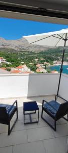 dwa krzesła i parasol na balkonie w obiekcie RITA - Charming 2-Bedroom Apartment with sea view, Slano w mieście Slano