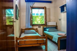 2 Betten in einem kleinen Zimmer mit Fenster in der Unterkunft Platamon village house in Platamonas