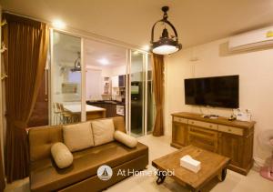 Ao Nang Mountain View Pool Villa في شاطيء آونانغ: غرفة معيشة مع أريكة وتلفزيون بشاشة مسطحة