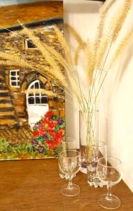 tre bicchieri di vino seduti su un tavolo con un dipinto di המקום של ענת. Anat's place a Tel ‘Adashim