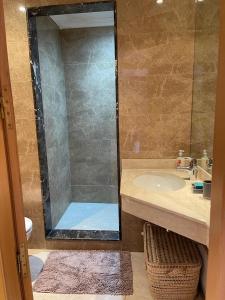 ein Bad mit einem Waschbecken und einer Dusche mit einem Spiegel in der Unterkunft Appartement gueliz Majorelle in Marrakesch