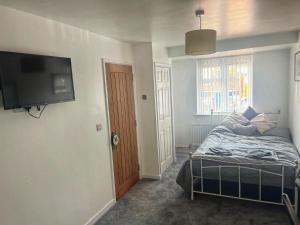 1 dormitorio con 1 cama y TV de pantalla plana en Modern comfortable quiet self contained apartments, en Brackley