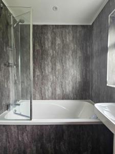 a bathroom with a bath tub and a sink at Modern comfortable quiet self contained apartments in Brackley