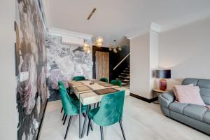 a dining room with a table and green chairs at APARTAMENTY Z TARASEM NA DACHU NA WYDMACH W MIĘDZYWODZIU in Międzywodzie