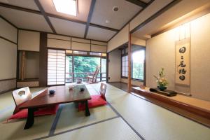 a dining room with a wooden table and chairs at Yumoto Ueyama Ryokan in Himeji