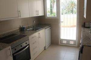 a kitchen with white cabinets and a sink and a window at Apartamento nuevo en urbanización a 250 metros de la playa in Denia