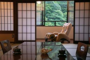a room with a table and a chair and a window at Yumoto Ueyama Ryokan in Himeji