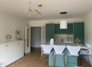 a kitchen with green cabinets and a table with white chairs at Appartement Victor Hugo 6 couchages in Biarritz