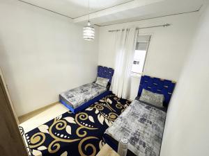 a small bedroom with two beds and a window at SAM HOUSE 2 min à l'aéroport in Tangier
