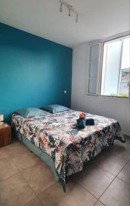 a bedroom with a bed with a flowered blanket and a window at Welcome to Baie Orientale plage - 4 personnes - max 6 personnes in Orient Bay