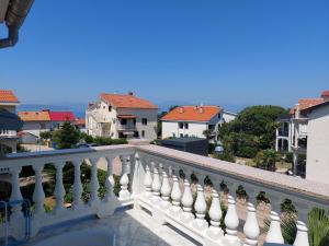 a balcony with a white railing and houses at Milka Apartments in Njivice