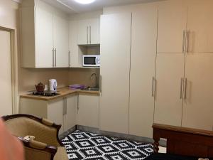 uma cozinha com armários brancos e um tapete preto e branco em Skinkikofi Guest House em Paarl