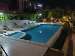 a swimming pool at night with chairs around it at Kadınlar den plajına 50 metre bahçeli 1+1 in Kuşadası