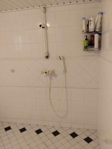 a shower with a hose in a white tiled bathroom at Villa Anna in Lahti