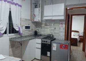una pequeña cocina con fogones y armarios blancos en Apart Maza en Maipú
