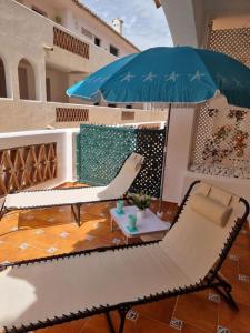 eine Terrasse mit Stühlen, einem Sonnenschirm und einem Tisch in der Unterkunft Quilla Apartment in Torrequebrada