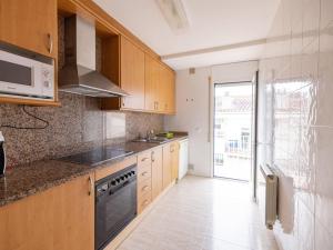 Fantástico y acogedor apartamento en Sant Feliu في سان فيليو دي غيكسولس: مطبخ بدولاب خشبي وفرن علوي موقد