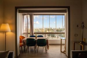 une salle à manger avec une table, des chaises et une grande fenêtre dans l'établissement Luxury golden view apartment in les terrasses danfa ain diab, à Casablanca