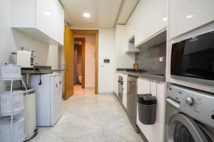 eine Küche mit einer Waschmaschine, einem Trockner und einer Mikrowelle in der Unterkunft Luxury golden view apartment in les terrasses danfa ain diab in Casablanca