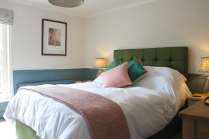 a bed with a green headboard and pillows on it at The George Inn St Mary Bourne in Saint Mary Bourne