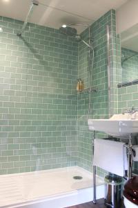 a bathroom with green subway tiles and a sink at The George Inn St Mary Bourne in Saint Mary Bourne