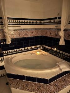 y baño con bañera grande y azulejos negros. en Hacienda Encanto del Rio, en Playa Es Figueral