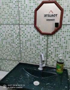 a bathroom with a sink and a sign on the wall at Mandala Camping - Oferecemos um espaço para sua barraca in Alto Paraíso de Goiás
