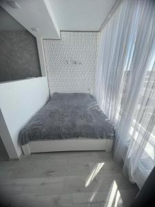 ein kleines Bett in einem Zimmer mit Fenster in der Unterkunft Квартира в центре, новострой in Tschernihiw