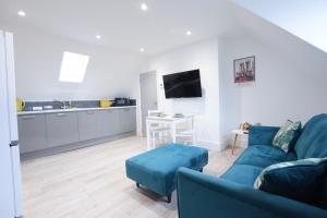 a living room with a blue couch and a kitchen at Stylish City Centre Apartments in Lincolnshire