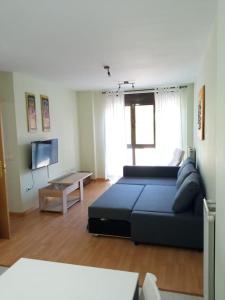 a living room with a blue couch and a tv at Apartamento LEILA in Posada de Llanes