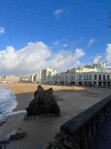 una playa con una roca en la arena y edificios en Sirona Bay Biarritz - Plages - Casino - WIFI - VOD en Biarritz