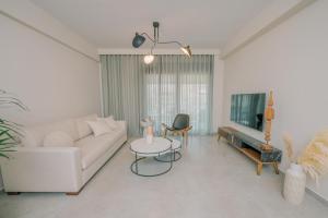 ein Wohnzimmer mit einem weißen Sofa und einem TV in der Unterkunft HAMA Luxury Seaside Apartments in Korinthos