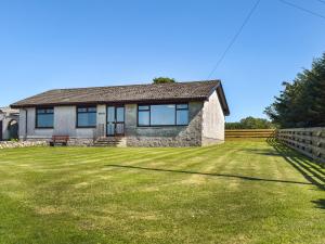 una casa con un patio de hierba delante de ella en Lowesmuir Cottage, en Cumnock