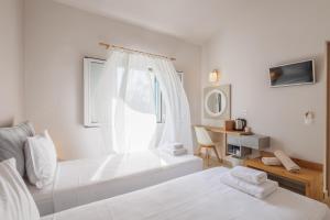 a white bedroom with two beds and a window at Satori Boutique Hotel in Acharavi