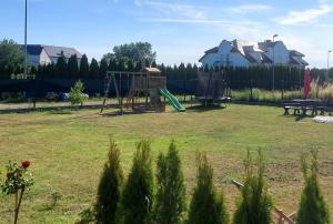 un parc avec une aire de jeux et une balançoire dans l'établissement Uroczy Zakątek 1, à Grzybowo