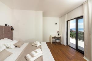 a white bedroom with a large bed and a window at Family House "Villa Gyra" with Private Swimming Pool, Indoor BBQ, Gym and Gaming room! in Podstrana +61 photos