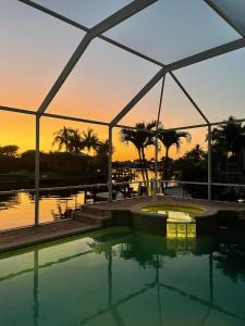 uma piscina com um pôr-do-sol ao fundo em Villa Magnolia em Cape Coral